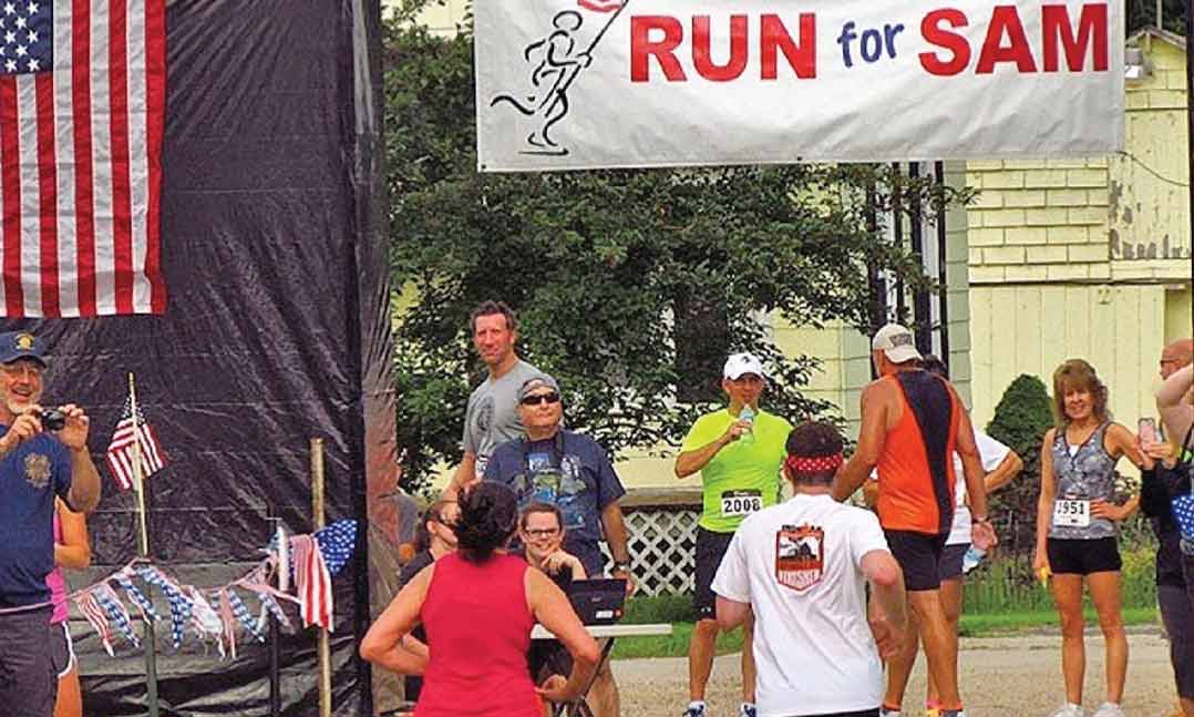 Runners cross the finish line during the Run for Sam in July 2021 in Princeton, Wisconsin.