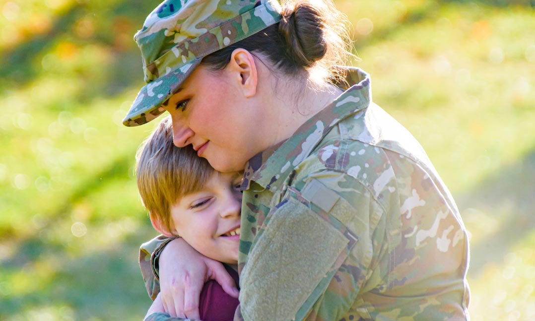 Uniformed service member hugging her child