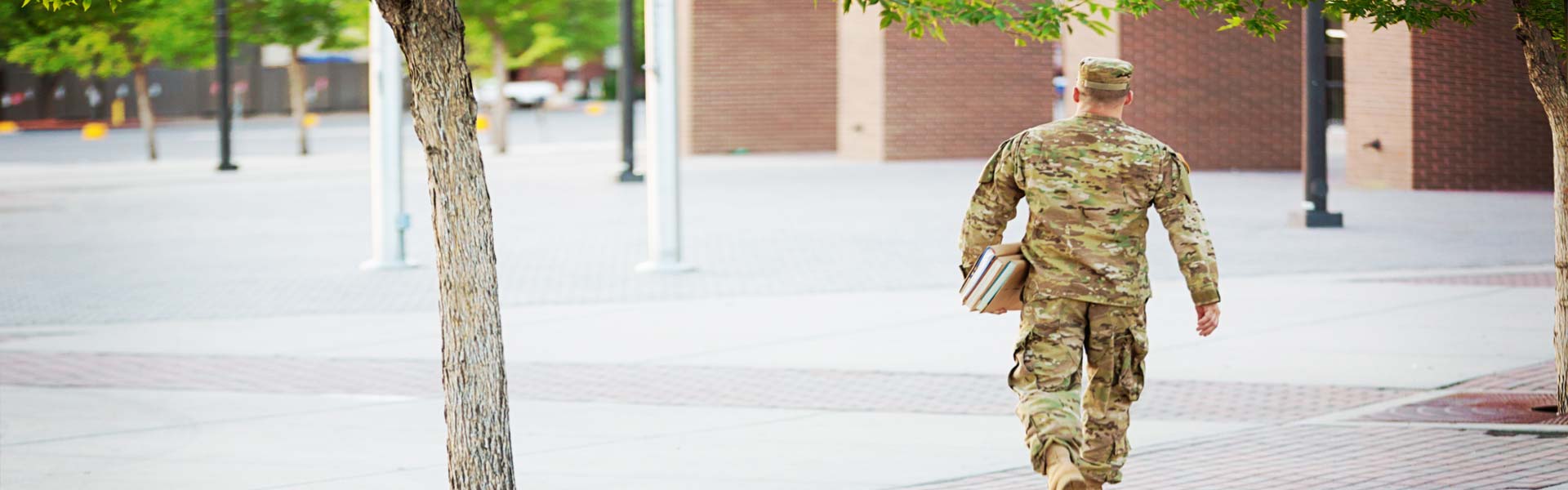 Service member walking away carrying college books