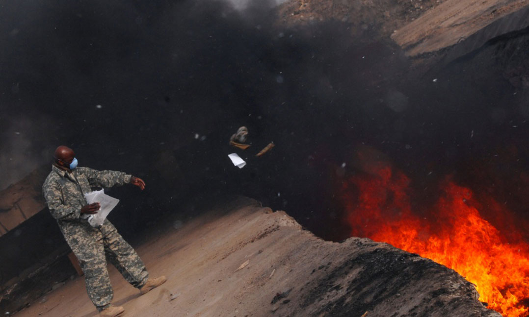 A member of the Air Force tosses items into a burn pit in Balad, Iraq