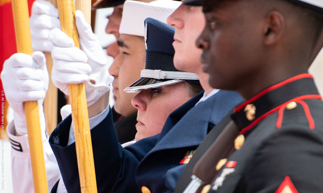 Men and women of a joint color guard stand at attention