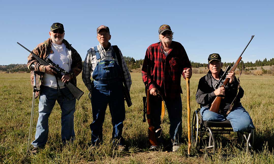  Four decorated Purple Heart veterans stand in a field with firearms while attending a special hunt on the Great Planes