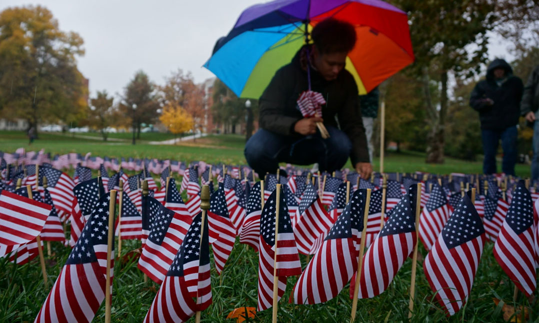 Student veteran placing US flags in ground memorial