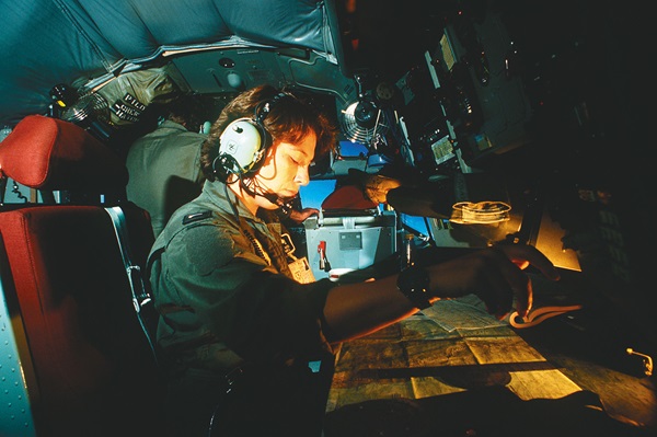 Woman navigator aboard a KC-135 Stratotanker checks her charts