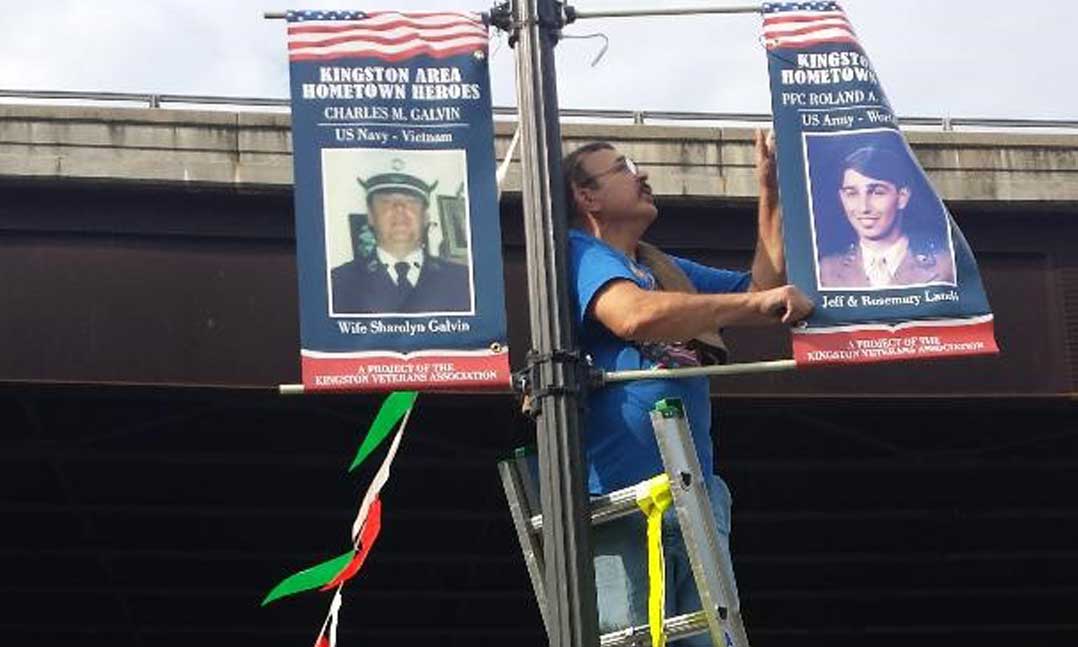 A man hangs banners that honor fallen veterans