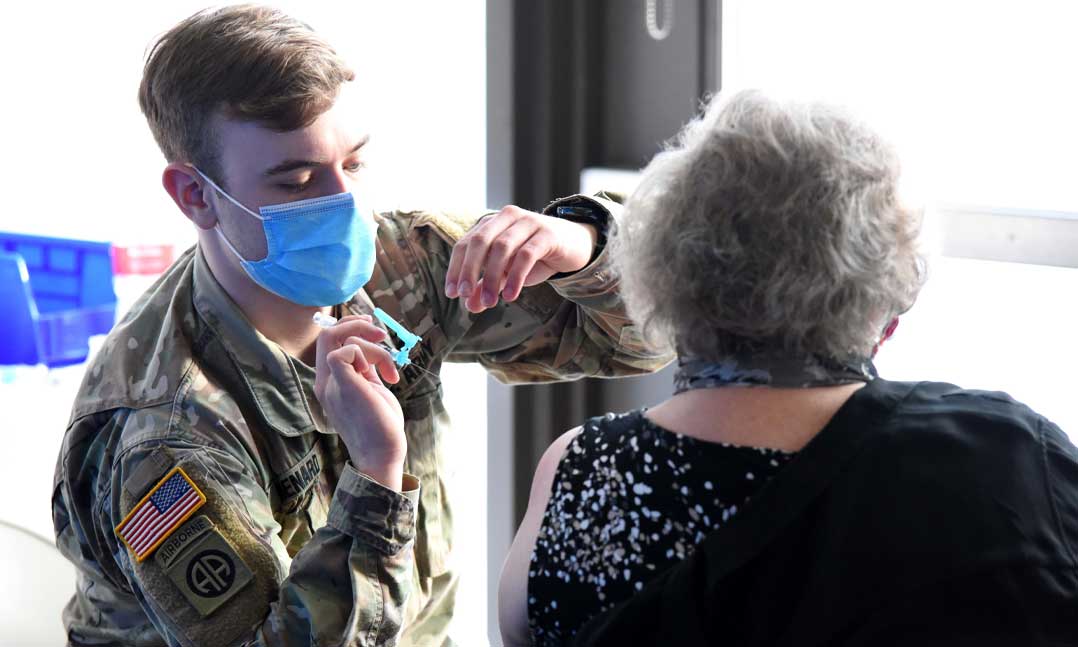A member of the Minnesota National Guard administers a shot to a patient