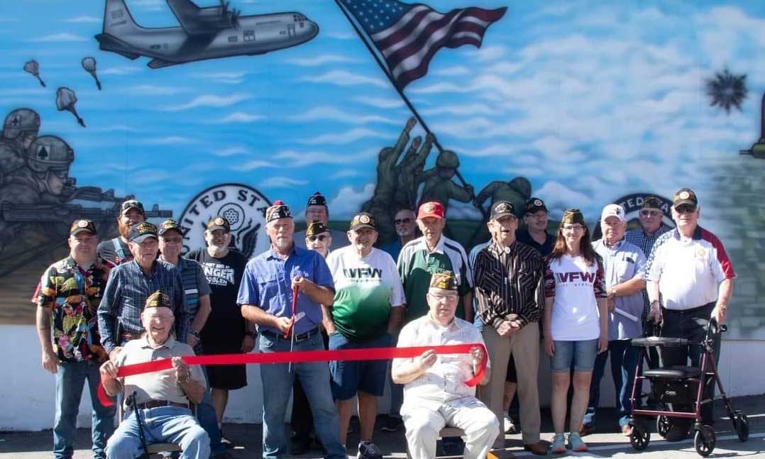 VFW Post members stand in front of painted mural on the side of their Post home