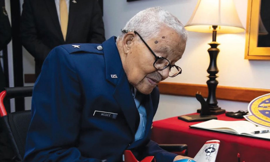 Retired Air Force Brig. Gen. Charles McGee, a Tuskegee Airman, signs a P-51 Mustang model