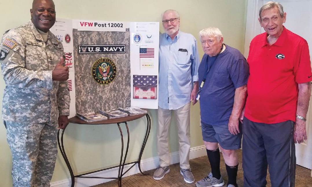 VFW Post 12002 member Dennis Parmer (left) shows off the new Veterans Resource Reading Area to veterans living at Brookmont Assisted Living in Woodstock, Ga., in June. Residents of the home have access to VFW magazine 24 hours a day thanks to the efforts of members of the Post in Alpharetta, Ga.