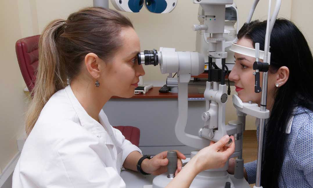 ophthalmologist looks at a patient's eyes during an exam