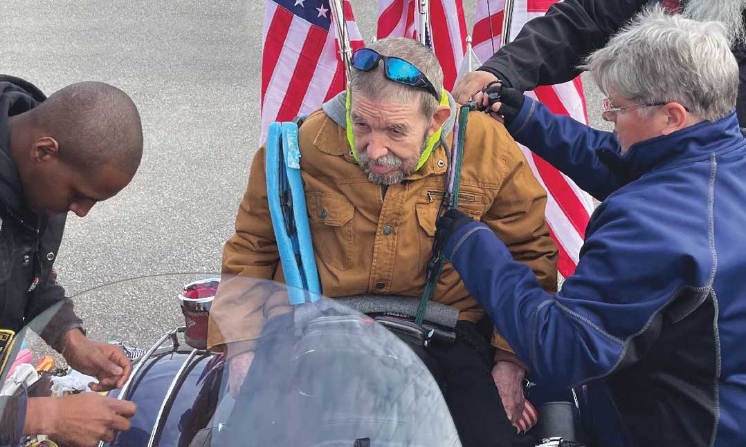 Members of VFW Post 637 Riders help Vietnam War veteran Michael Polsley get ready for a motorcycle ride
