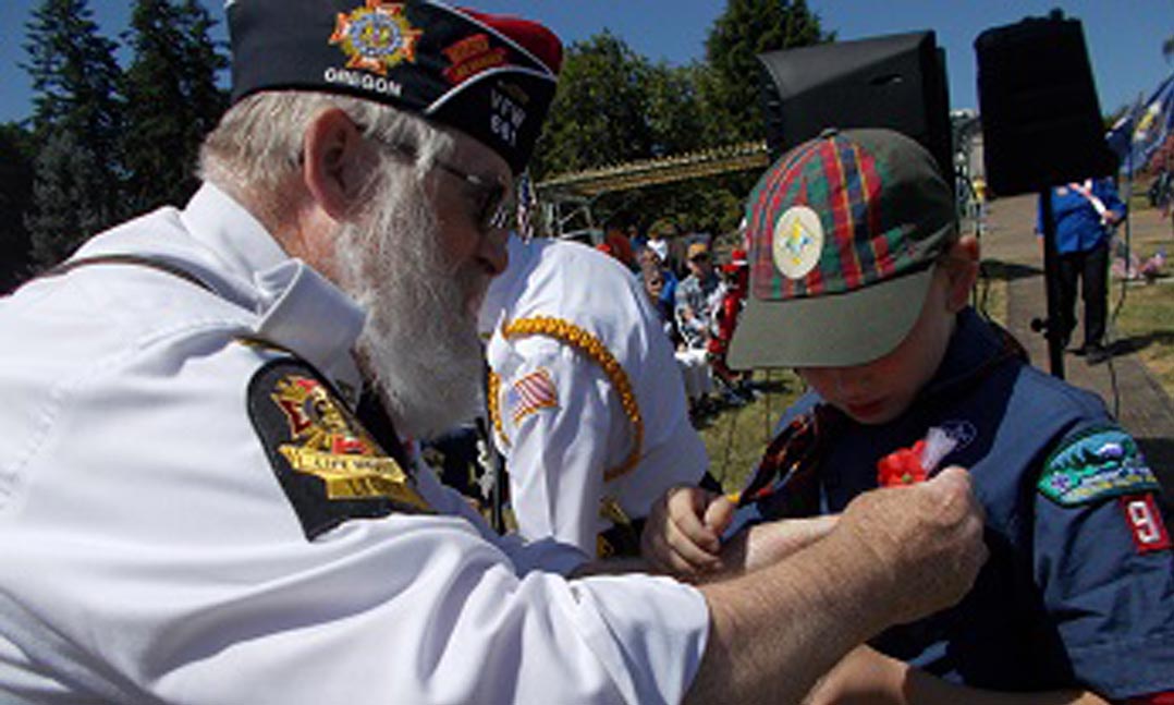 VFW Post 661 Quartermaster Kerry Wymetalek pins a Buddy Poppy to a Boy Scout’s uniform during a Memorial Day service
