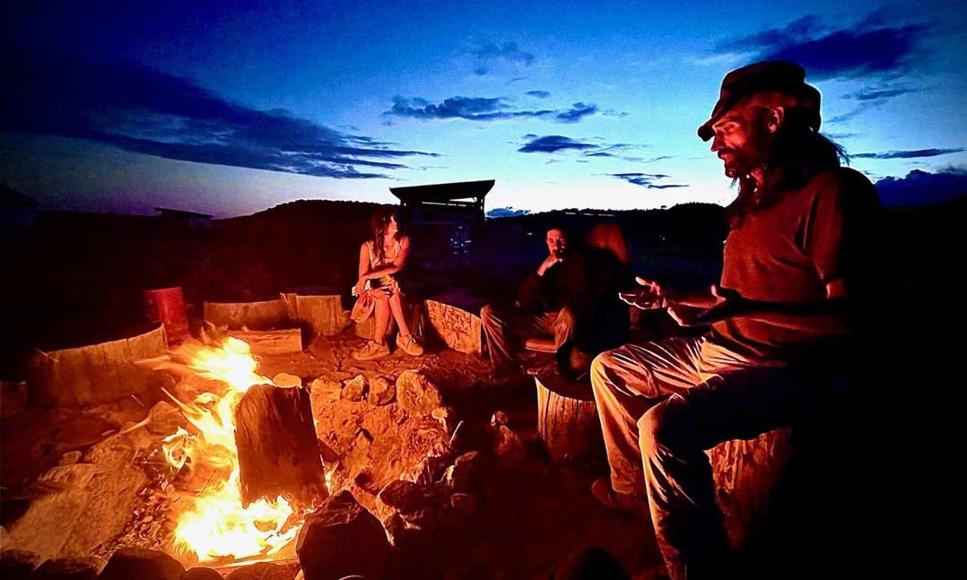 Veterans gather around a fire in a self-sufficient desert community