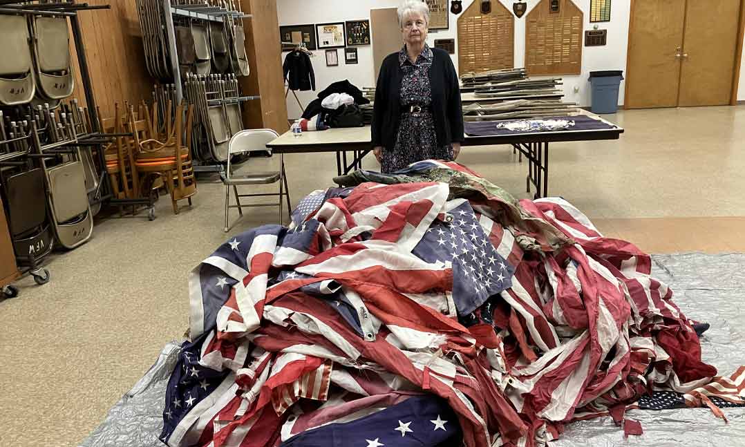 Auxiliary member Dixie Westerlund stands in front of retired U.S. flags