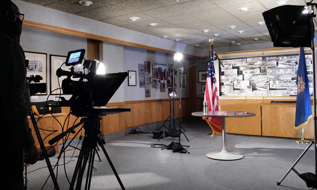 Camera set up in front of a table and flags for an upcoming interview