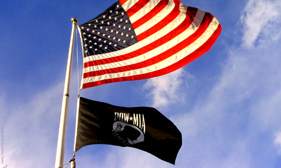 A black POW-MIA flag flying beneath an American flag
